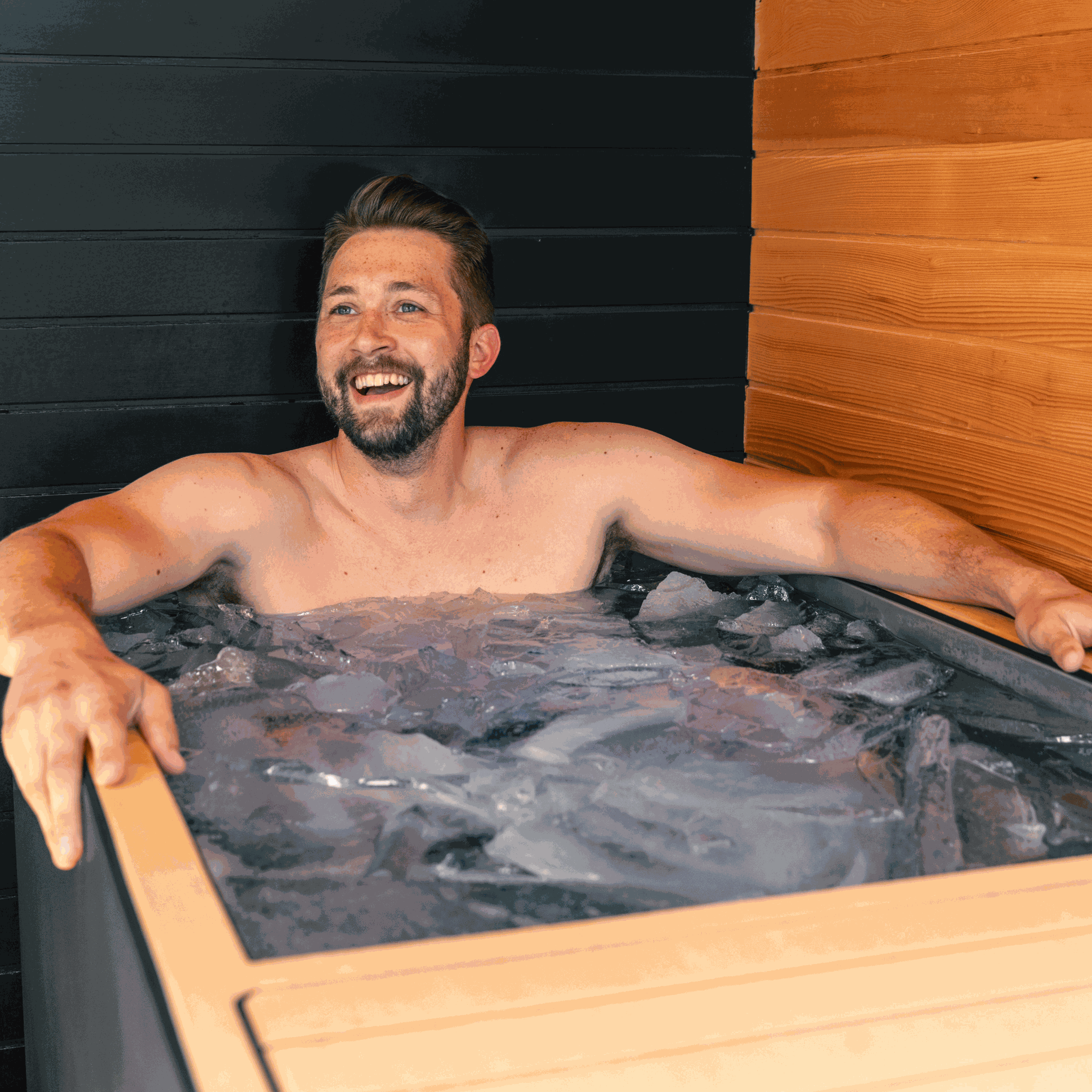 Man enjoying ice-cold therapy in a Luxury Plunge cold plunge tub with ice and sleek wooden surroundings