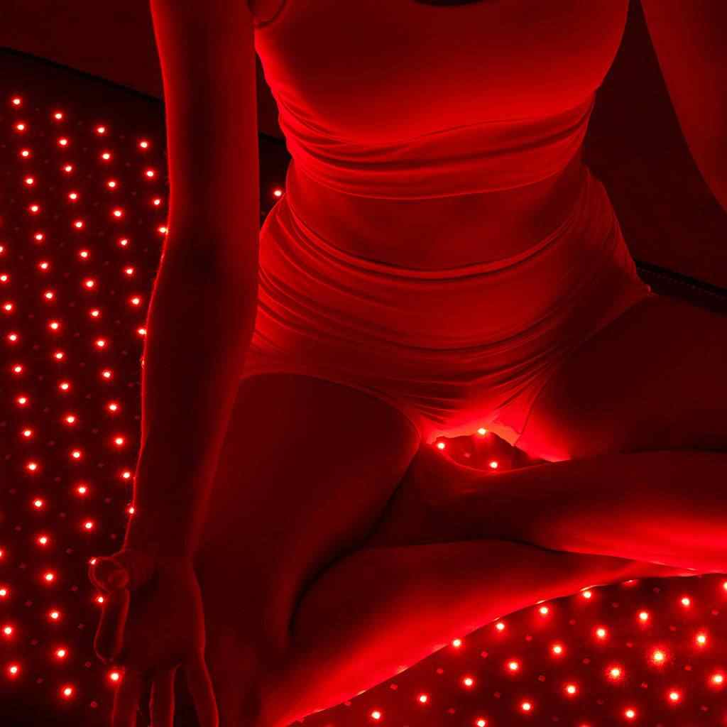 Person using Nushape Red Light Therapy Mat emitting 660nm and 850nm LED light for full-body healing and recovery