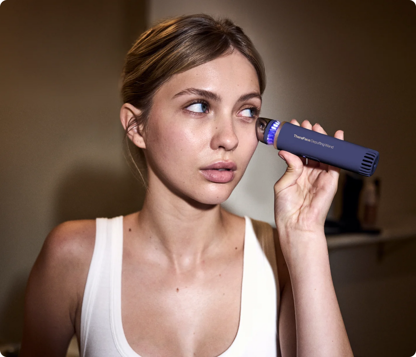 Woman using TheraFace Depuffing Wand for under eye hot and cold treatment to reduce puffiness and dark circles