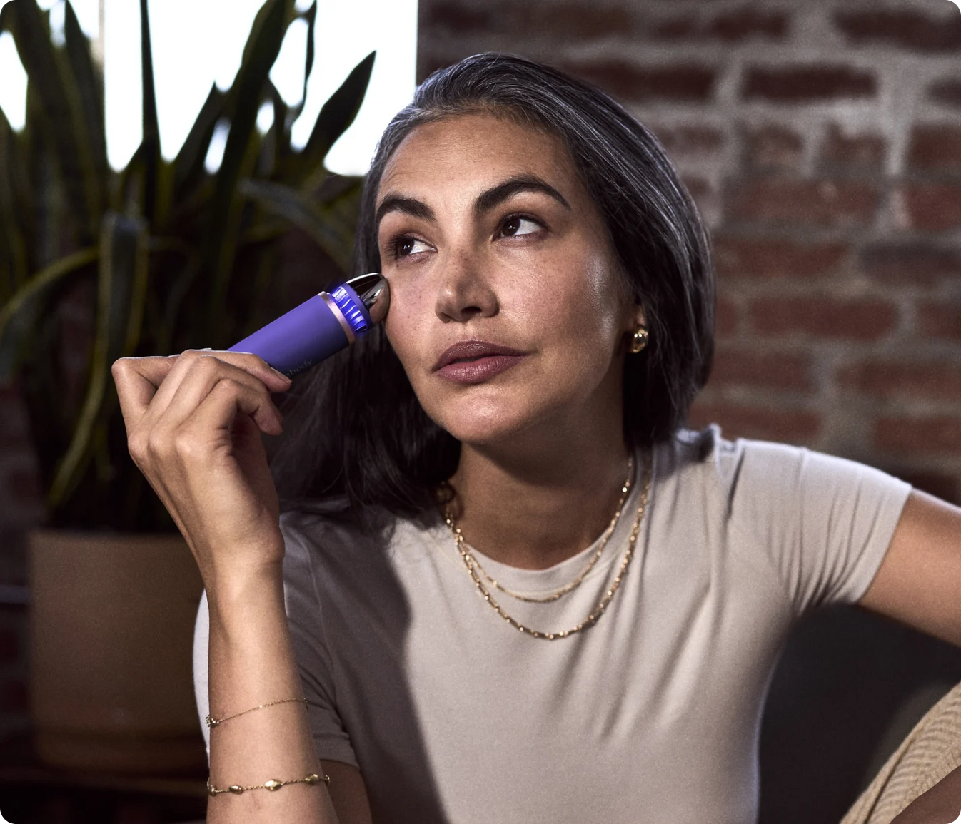 Woman using TheraFace Depuffing Wand for under-eye treatment to reduce puffiness and dark circles