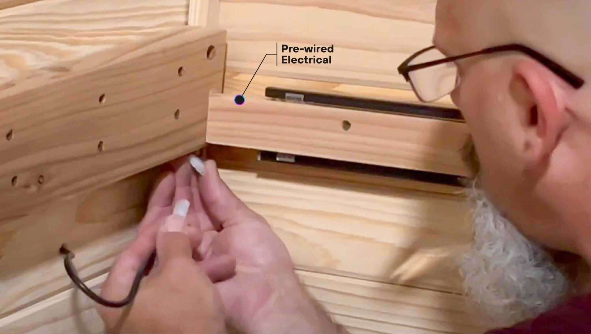 Man installing pre-wired electrical connection inside wooden Plunge Pod + Sauna Mini Bundle infrared sauna unit