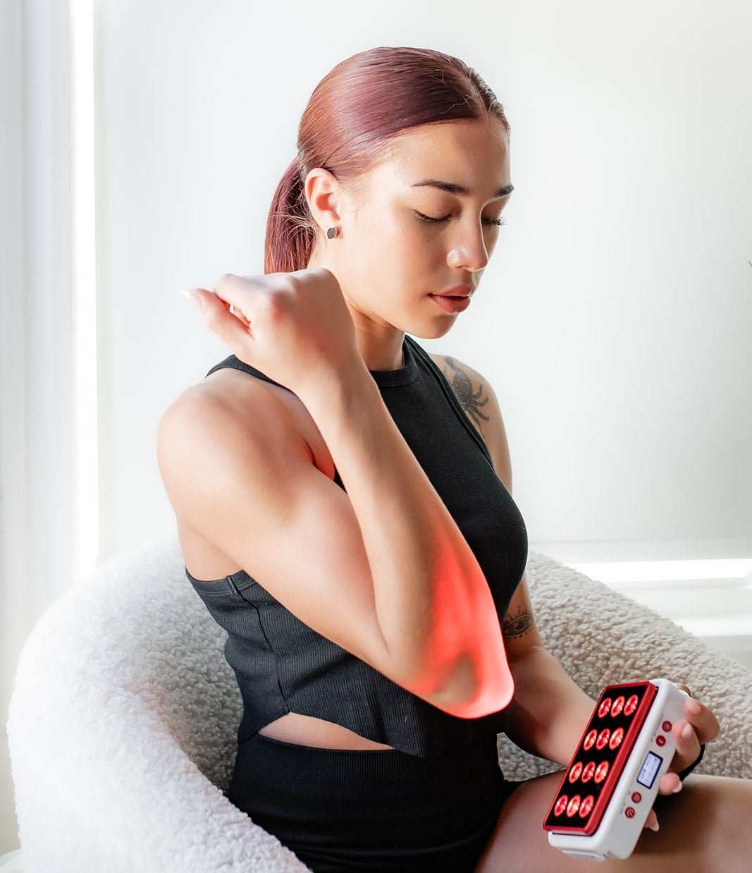 Woman using MitoPRO Mobile portable red light therapy device on elbow