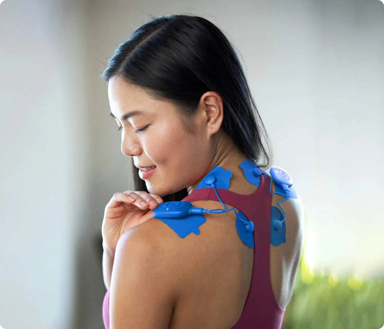 Woman using Power Dot DUO TENS and NMES muscle stimulator on shoulders