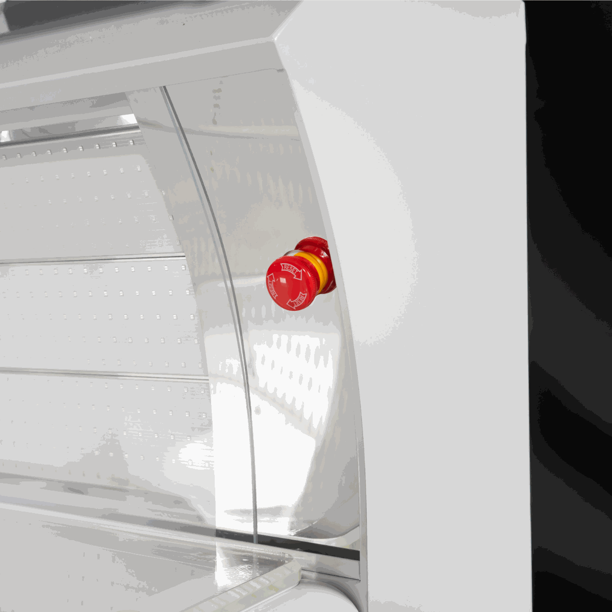 close-up of red light therapy bed showing red emergency stop button and LED lights panel inside white frame