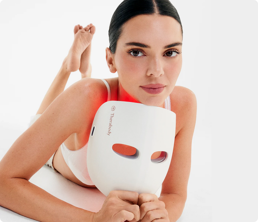 Woman holding TheraFace Mask cordless LED light therapy device for skin rejuvenation