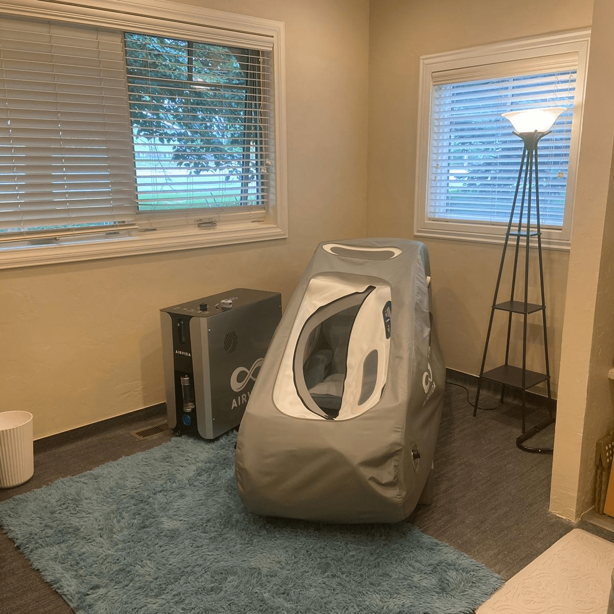 Airvida Pro90 portable seated hyperbaric chamber with soft-shell design and premium folding chair in a home wellness setting