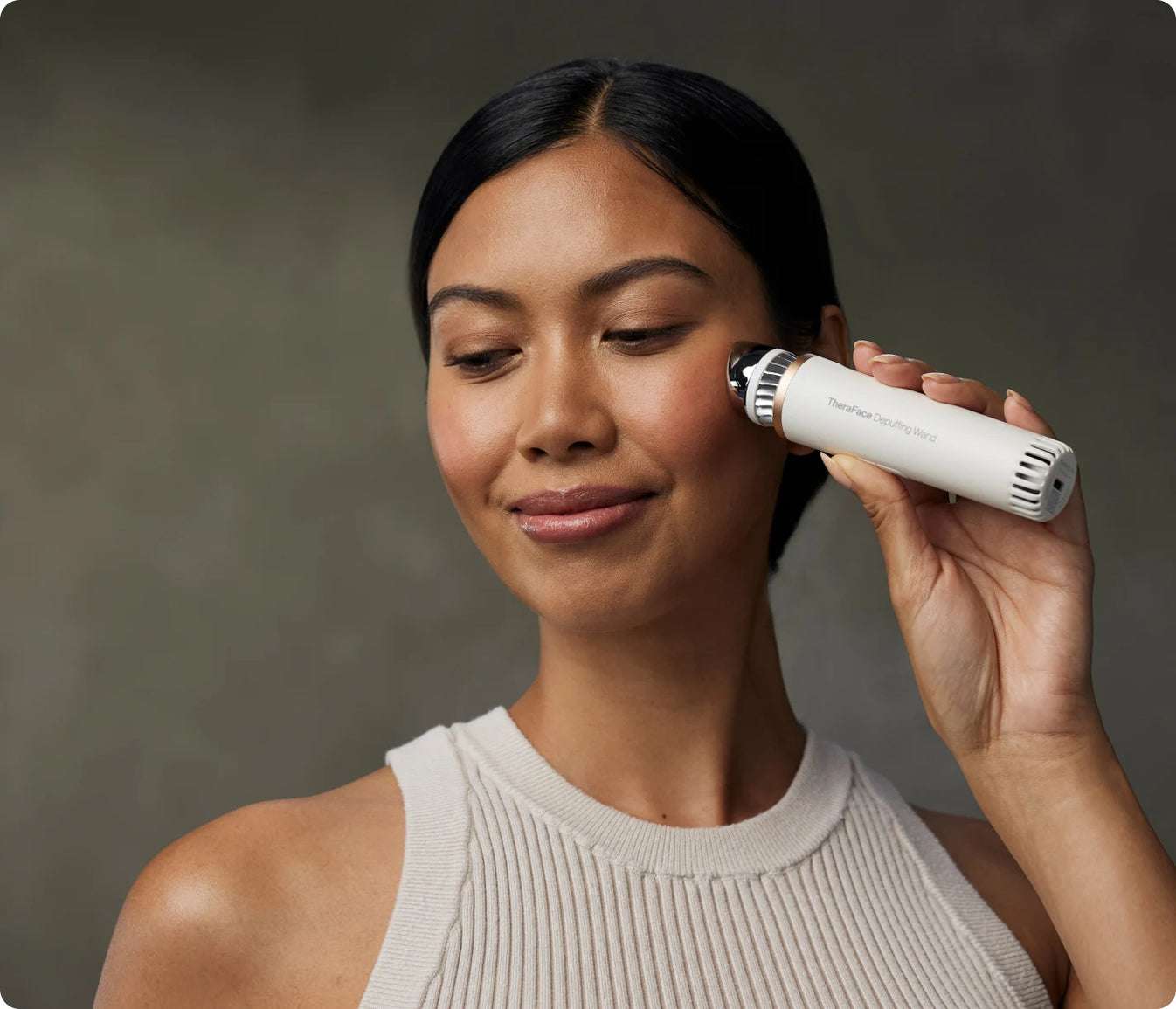 Woman using TheraFace Depuffing Wand for hot and cold under-eye treatment