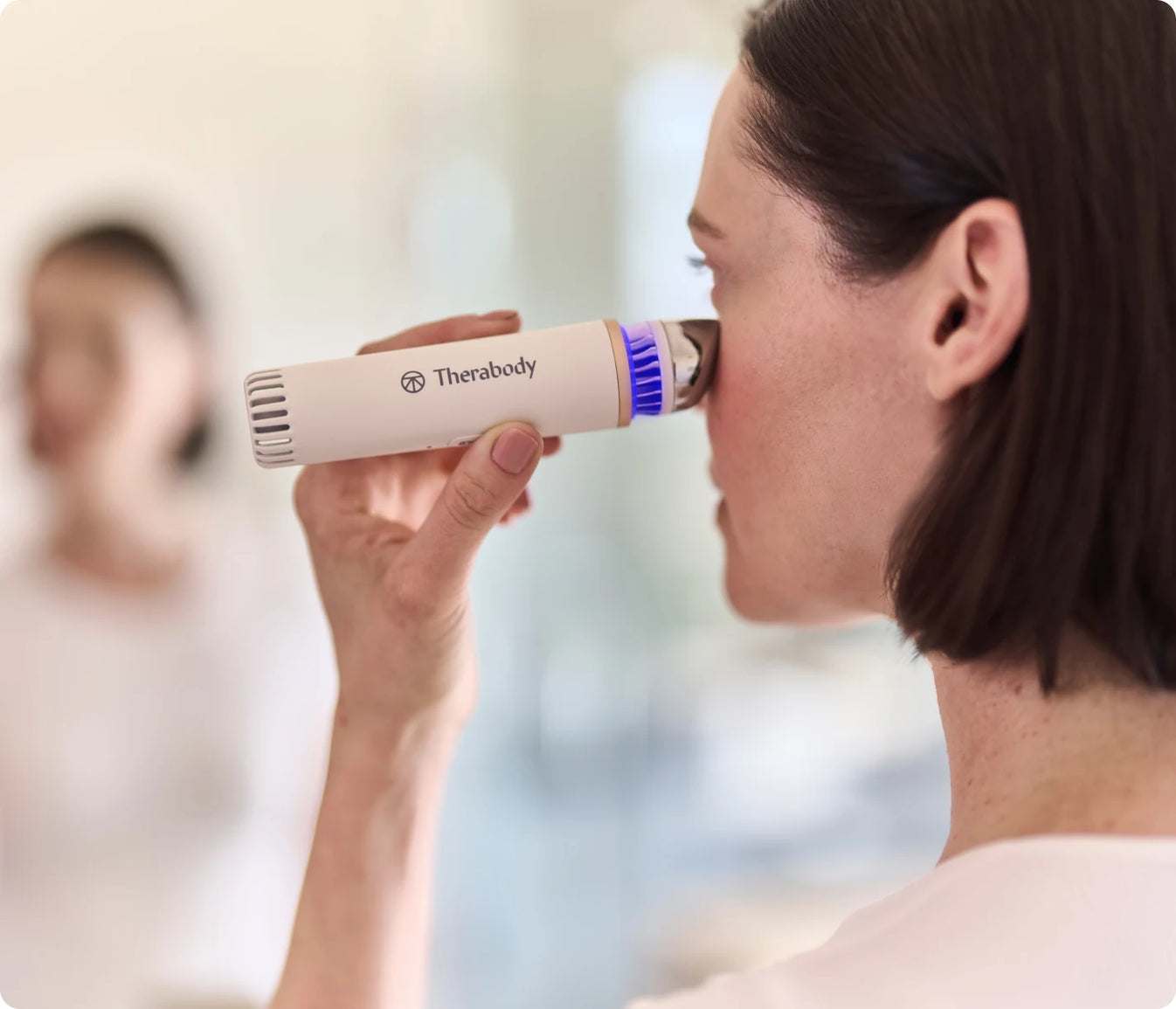 Woman using TheraFace Depuffing Wand for hot and cold under-eye treatment