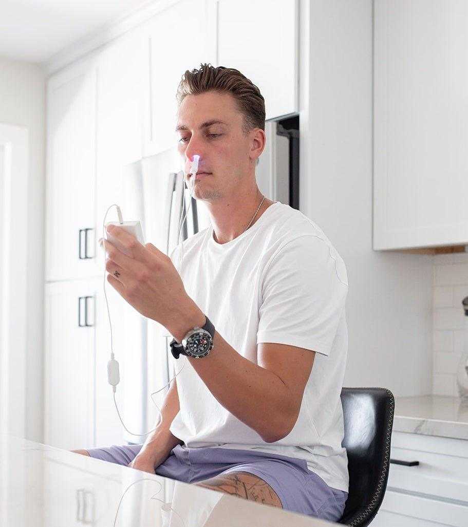 Man using MitoBOOST™ Systemic Intranasal Device for sinus health and immune support in kitchen