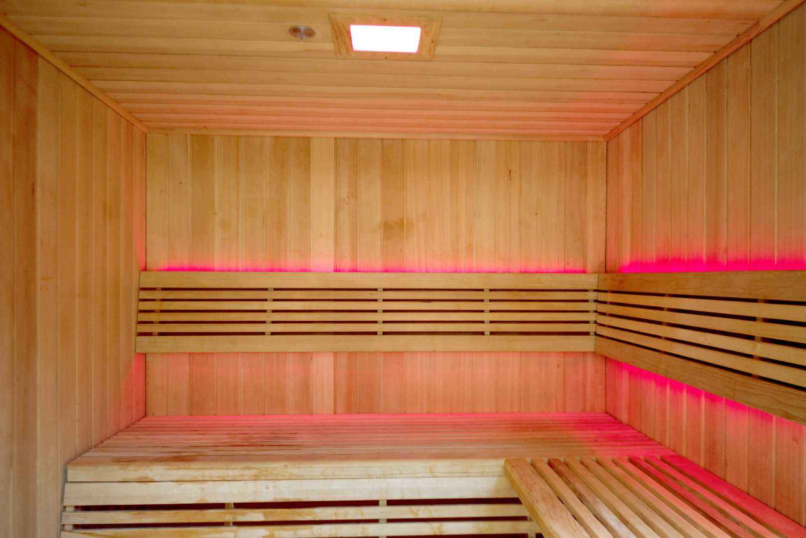 Traditional sauna interior with hemlock wood panels, red LED lighting, and wooden bench seating