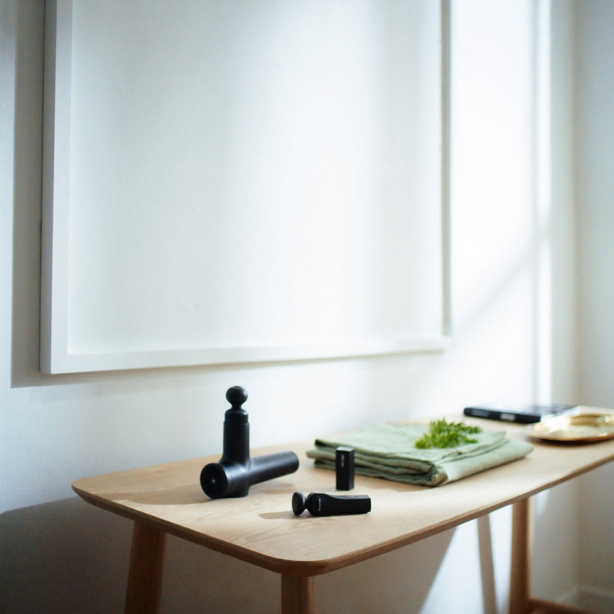 Percussion massage guns on an oak side table