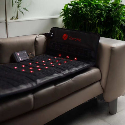 TheraPro large PEMF infrared red light healing pad on a couch with control unit