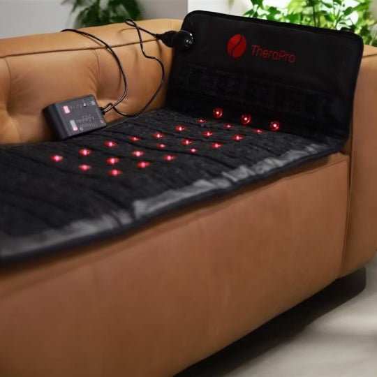 TheraPro PEMF infrared red light therapy pad with red LED lights on black mat for pain relief and relaxation