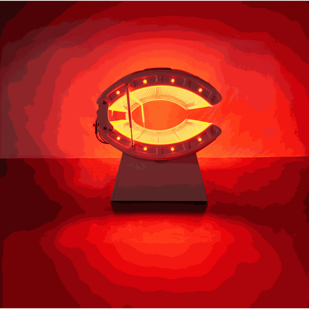 Red light recovery system bed emitting red light on a white stand against red background