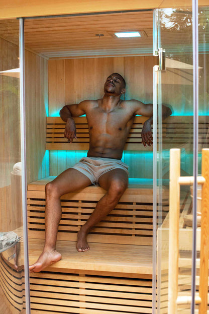 Man relaxing in a modern traditional sauna with wooden interior and LED lighting